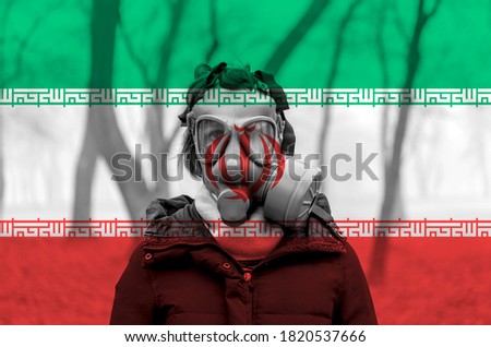 Photo of woman wearing protective gas mask against the background of the Iran flag. 