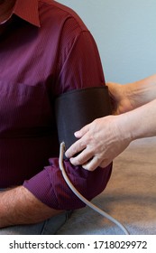 Photo of a woman's hands placing a blood pressure cuff around a man's arm.