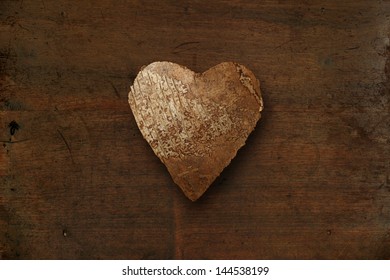 Photo of a wood heart on top of an old dark wood background. 