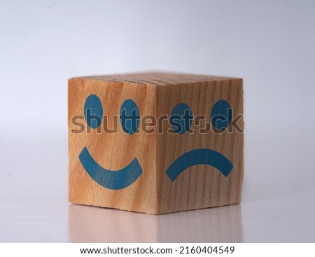 Photo of a wooden cube with happy and sad facial expressions as a symbol of instant personality shifts. Concept of bipolar , unipolar and borderline mental disorder.
