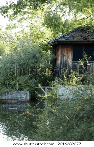 Photo of a wooden house that has a pond in front of it. This was taken at the Botanical garden in Niagara Falls, Canada