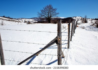 A Photo Of Wooden And Metal Fence In Winter Field