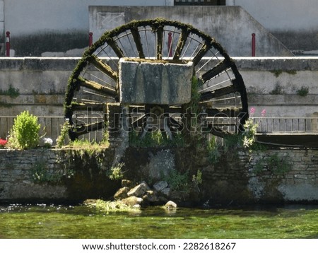 Photo of a wooden paddle wheel that operates on the Sorgue river in the center of a famous procencal village. This photo was taken at Fontaine de Vaucluse in Provence.