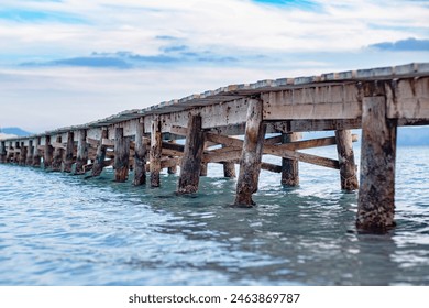 Photo of a wooden pier extending into the sea. Nice side view of the pier. Calm turquoise sea water, wooden bridge structure and beautiful sky. - Powered by Shutterstock