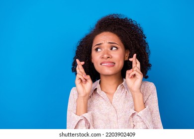 Photo Of Worried Nervous Lady Bite Lips Crossed Fingers Look Empty Space Isolated On Blue Color Background