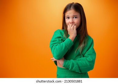 Photo Of Worried Nervous Teen Girl Afraid Of Something Against Orange Background