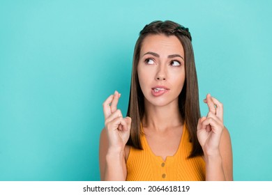Photo Of Worried Young Lady Hold Fingers Crossed Look Empty Space Isolated On Teal Color Background