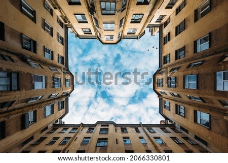 Photo of yellow courtyard well in old residential house from historical center of Saint Petersburg, Russia. Cloudy blue sky. The facade with many windows. Travel destination concept. Copy space.