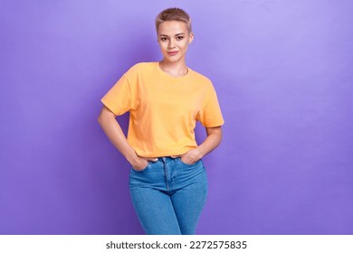 Photo of young adorable confident lady wear denim jeans hands pockets orange t-shirt posing model advert banner isolated on purple color background - Shutterstock ID 2272575835