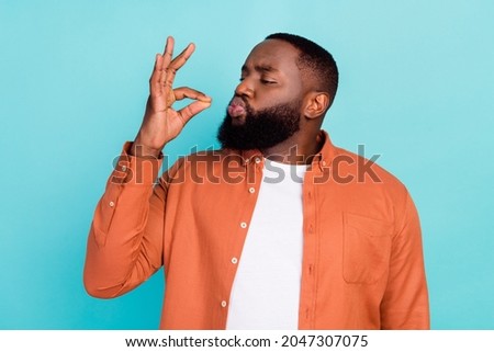 Photo of young african man show fingers tasty delicious perfect gourmet sign isolated over turquoise color background