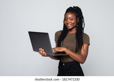 Photo Of Young African Woman Standing Over Grey Wall With Laptop Computer.