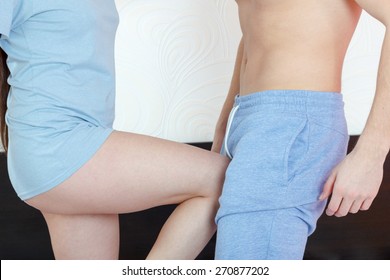 Photo of young angry woman in panties kicking with leg handsome half naked man in groin or genitals with painful face expression. Defense against sexual assault in bedroom. Fight against violence.
