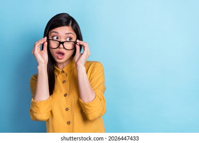 Photo of young asian girl amazed shock fake novelty rumor hands touch eyeglasses look empty space isolated over blue color background