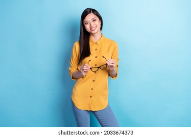 Photo of young attractive asian business woman happy positive smile hold eyeglasses isolated over blue color background