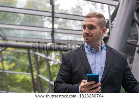 Photo of a young and attractive business man checking his phone. Wearing smart casual clothes. Entrepeneur style