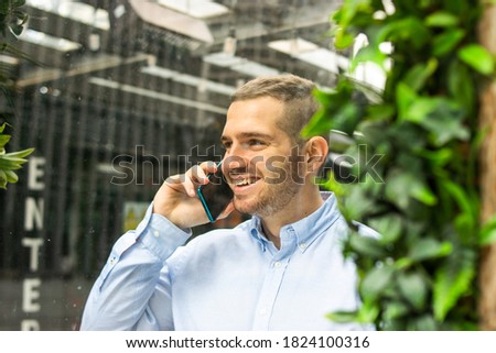 Photo of a young and attractive business man wearing smart casual and elegant clothes talking on the phone while smiling. Smart working. Entrepeneur