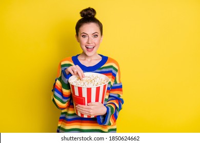 Photo of young attractive woman happy smile hold pop-corn box eat watch movie isolated over yellow color background