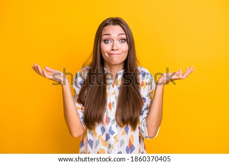 Photo of young attractive woman shrug shoulders clueless confused no answer decide isolated over yellow color background