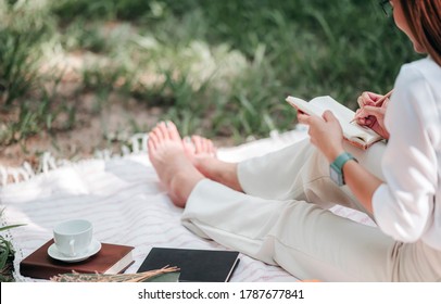 Photo of young attractive woman writing on diary while sitting outdoors in the park. - Powered by Shutterstock