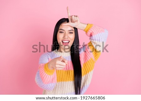 Photo of young beautiful funky smiling asian girl bullying teasing point finger you isolated on pink color background