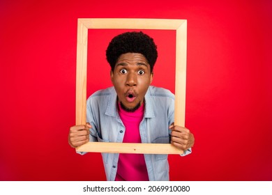 Photo Of Young Black Guy Amazed Shocked Wooden Frame Omg Wow Reaction Picture Isolated Over Red Color Background