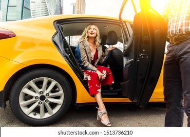 Photo of young blonde in long dress sitting in back seat of taxi in afternoon