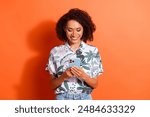 Photo of young brown haired curly lady in summertime season style shirt using smartphone using twitter isolated on orange color background