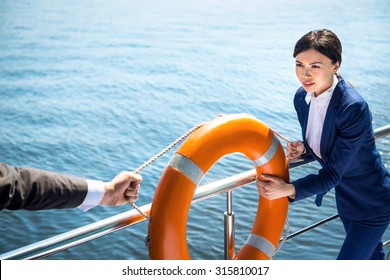 Photo Of Young Business Woman Standing Near River. Woman Holding Orange Life Preserver. Woman Seriously Looking At Her Opponent