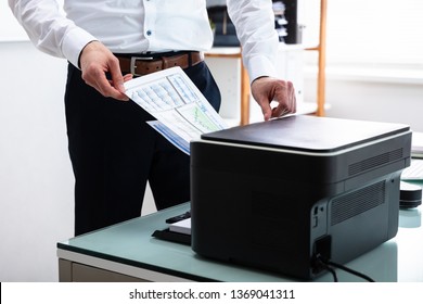 Photo Of Young Businessman Using Printer In Office