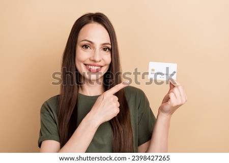 Photo of young businesswoman in khaki t shirt point finger new ecard features for business owners isolated on beige color background