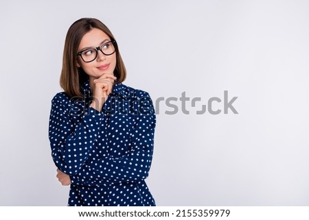 Photo of young charming lady hand touch chin look empty space guess interested wonder isolated over grey color background