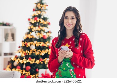 Photo Of Young Charming Lady Wear Ugly Red Sweater Hold Her New Smartphone Present From Her Friends Satisfied User Smiling New Year Party Indoors