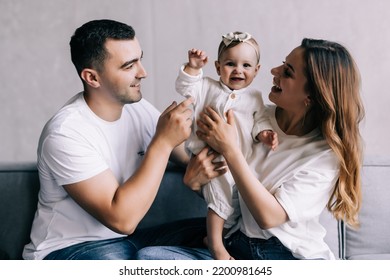 Photo Of Young Cheerful Family Happy Positive Smile Mommy Daddy Daughter Laugh Look Each Other Sit Sofa Indoors