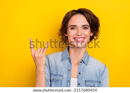 Photo of young cheerful girl good mood show fingers rock symbol isolated over yellow color background