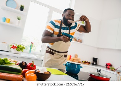 Photo of young cheerful guy good mood cooking dinner taste yummy fresh soup cuisine culinary indoors - Powered by Shutterstock