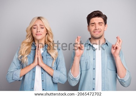 Photo of young couple ask beg wish hope luck success pleading waiting wish isolated over grey color background