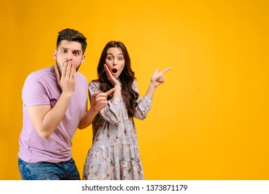 Photo Of Young Couple Man And Woman Surprised Pointing At Copy Space  Isolated Over Yellow Background