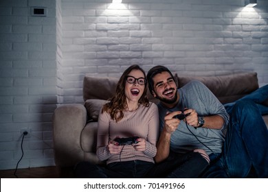 Photo Of Young Couple Playing Video Games At Home At Night.