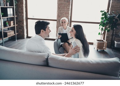 Photo of young couple sit sofa smiling psychotherapist office mature woman psychologist doctor consults relationship problems family life - Powered by Shutterstock