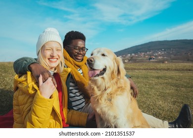 Photo of a young couple and their dog camping in the woods on a beautiful autumn day; spending time outdoors and appreciating nature. Couple playing with dogs - Powered by Shutterstock