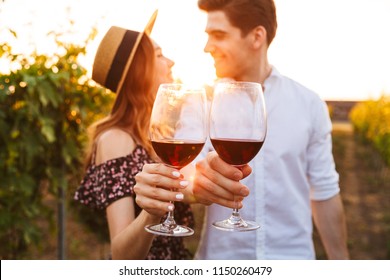 Photo of young cute happy loving couple outdoors drinking wine. Focus on glasses. - Powered by Shutterstock