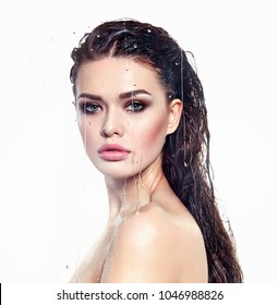 photo of a young dark-haired girl with a make-up smokey holding her hands on a glass with water drops on a white background.Fashion, beauty, natural appearance, spa, nude, beauty salon, natural.
