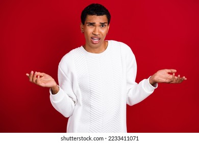 Photo of young dissatisfied guy wear white jumper dont know shrug shoulders how solve problems with xmas gifts isolated on red color background - Shutterstock ID 2233411071