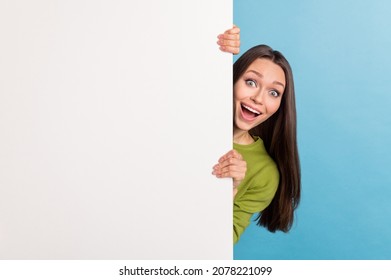 Photo of young excited girl hiding behind white wall advertise blank card isolated over blue color background - Powered by Shutterstock