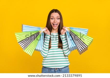 Photo of young excited girl shopping bags store discount present new collection isolated over yellow color background.