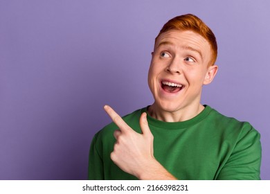 Photo of young excited guy look indicate finger empty space promo advertise isolated over violet color background