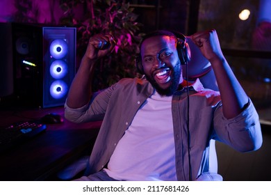Photo of young excited man rejoice success fists hands win battle triumph champion sit stool indoors - Shutterstock ID 2117681426
