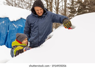 Photo Of A Young Father And Child Brushing And Shoveling Snow And Ice Off Car After Heavy Storm. Single Parent And Kid With Winter Scraper Clearing Family Car After Overnight Snow Blizzard. 