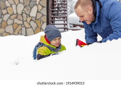 Photo Of A Young Father And Child Brushing And Shoveling Snow And Ice Off Car After Heavy Storm. Single Parent And Kid With Winter Scraper Clearing Family Car After Overnight Snow Blizzard. 