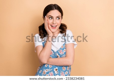 Photo of young girl brown ponytails curls touch cheek look empty space wear overall enjoy new tv series isolated on beige color background